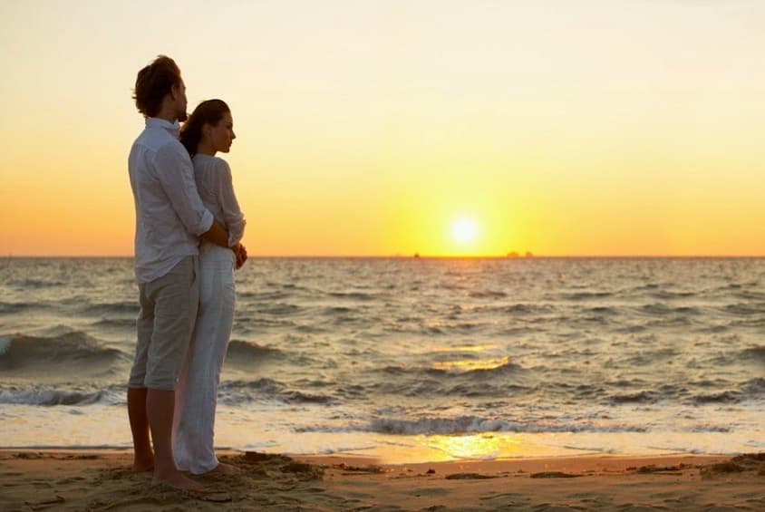 A couple watching a romantic sunset beside the ocean