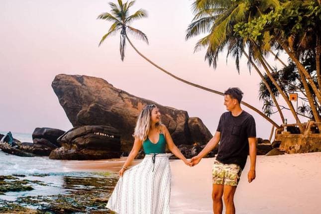A couple walking hand in hand along a tropical beach